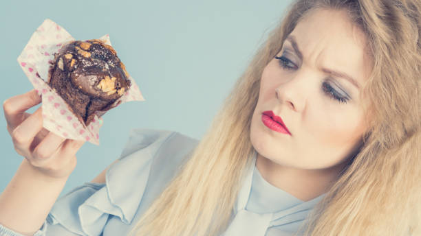 istock Skeptical woman holding chocolate cupcake muffin 898133776
