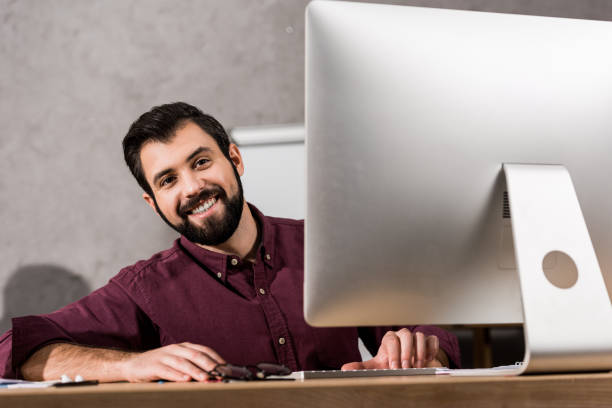 istock smiling businessman sitting at computer in office 898136254
