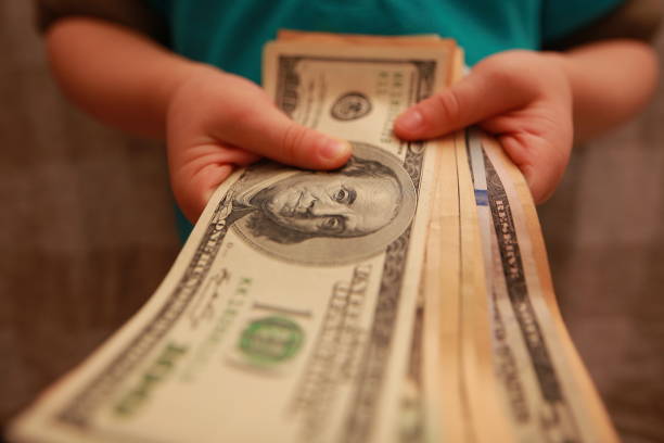 istock dollars in the hands of a child 898137500