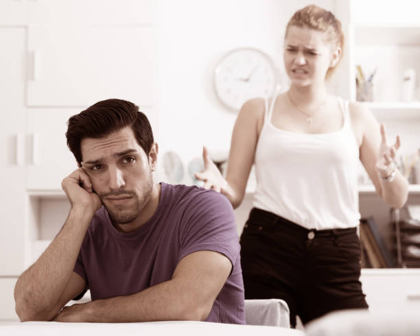 istock Stressed man at table with screaming wife behind 898137866