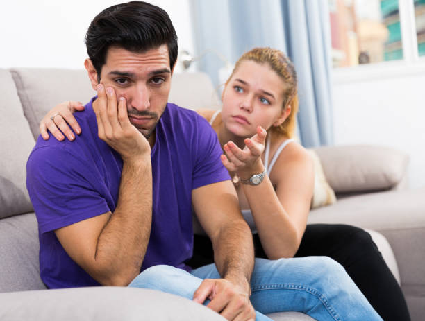 istock Ggirl comforting upset boyfriend on sofa 898137914