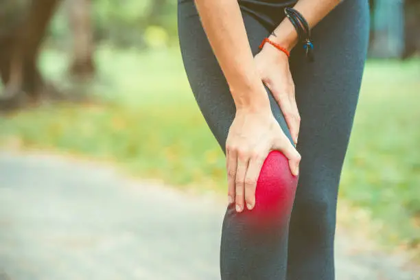 Woman holding her knee with red painful during a workout session sport. Pain relief concept