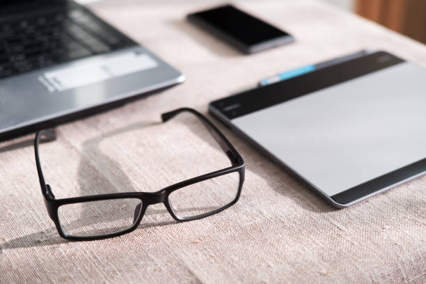 istock glasses near the computer on the Desk, phone and tablet operating environment 898168780