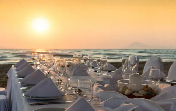 Luxurious dinner table setup on the beach during sunset