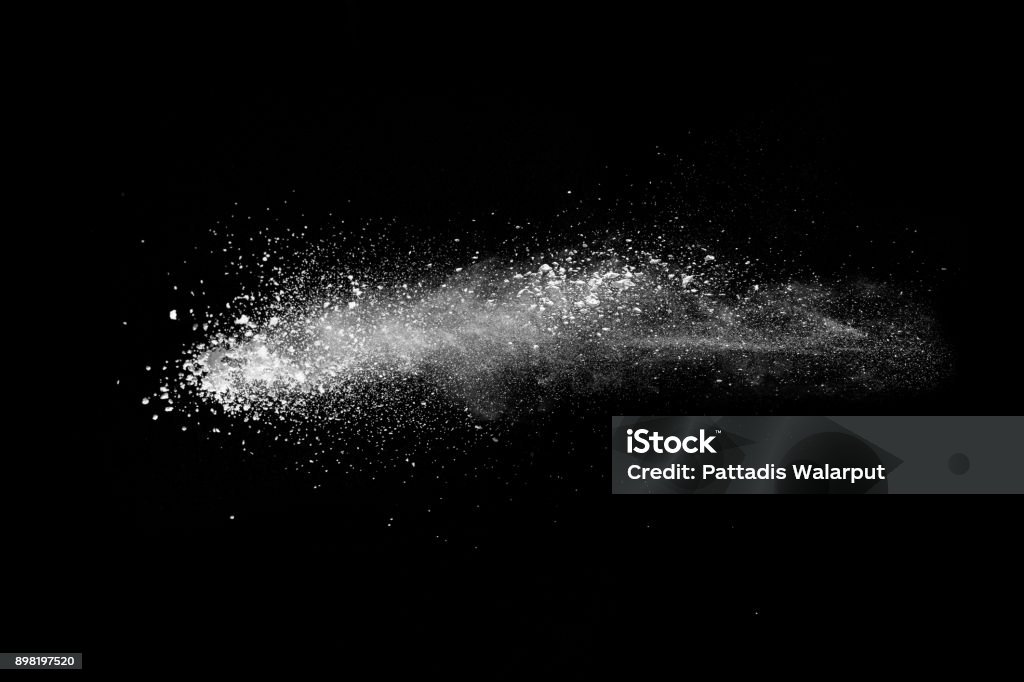 Freeze motion explosion of white dust on  black background. By throwing talcum powder out of hand. Stopping the movement of white powder on dark background. Snow Stock Photo