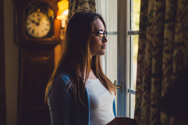 woman looking through the window - waiting women clock boredom imagens e fotografias de stock