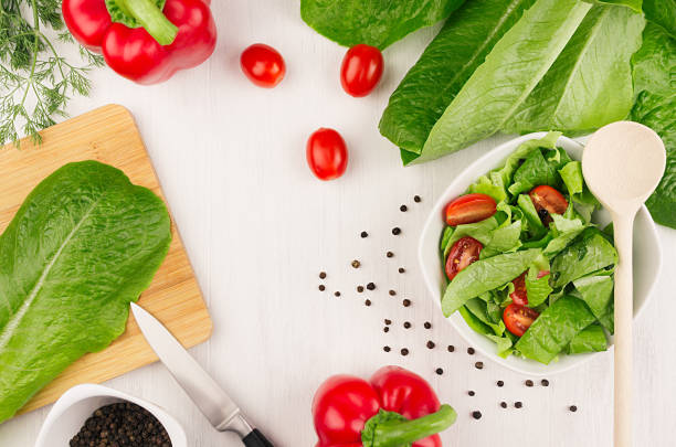 insalata fresca di foglie verdi, pomodorini rossi, paprika e ingredienti, posate su tavola di legno bianco, vista dall'alto. - cooking oil olive oil nutritional supplement spoon foto e immagini stock