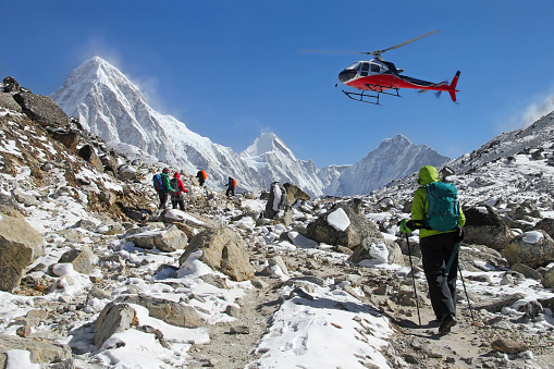 Goup of climbers in the Himalayas, view on peaks Lingtren, Pumori and Khumbutse. Rescue helicopter in action, Nepal