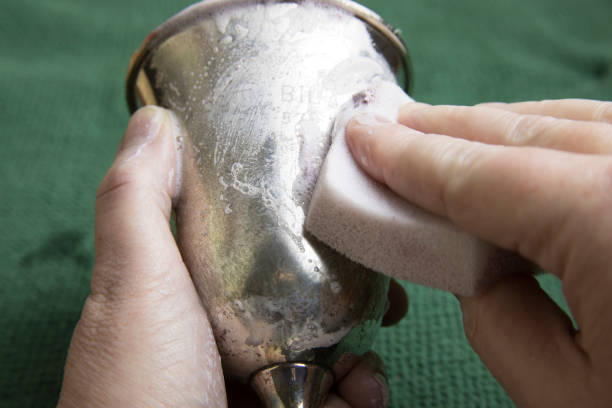 Hands polishing tarnished silver goblet stock photo
