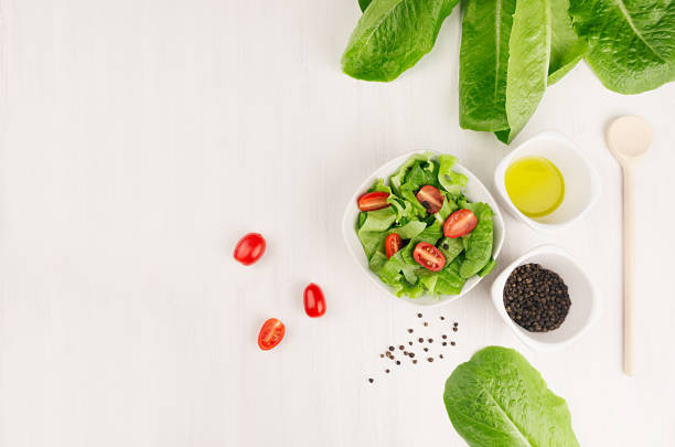 ingredients for healthy vegetarian spring salad -  fresh greens, tomatoes, spinach, olive oil and pepper on white wood background, top view, copy space. - cooking oil olive oil nutritional supplement spoon imagens e fotografias de stock