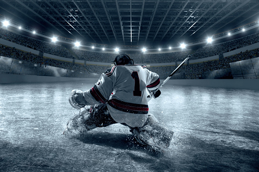 Ice hockey goalkeeper protects the goal on big professional arena. Goalkeeper dressed in a non-branded sports ice hockey uniform.