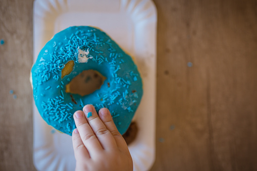 Young toddler girl touching a blue doughnut.