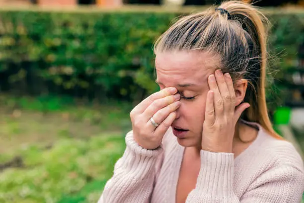 Woman with headache. Seasonal allergies and health problems. Sinus ache causing very paintful headache. Unhealthy woman in pain. Sharp strong sore. Flu cold or allergy symptom. Sinus pain, sinusitis.