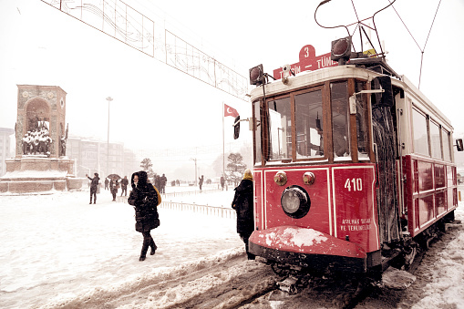 Istanbul, Turkey - January 7, 2017: The red nostalgic tram in Taksim Square on a snowy winter day. The tram carries passengers from Taksim to Tunel, Beyoglu.