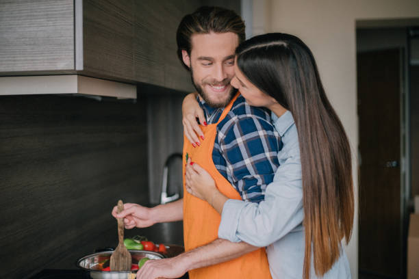 istock Girlfriend hugging boyfriend while he's preparing food 898225836