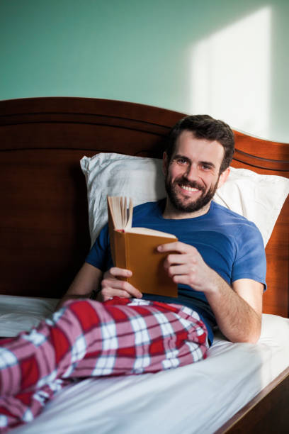 istock Young man reading a book in his bedroom 898238018