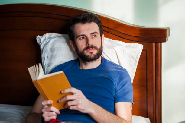 istock Young man reading a book in his bedroom 898238028