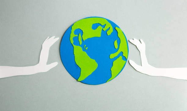 istock Paper cut design. Raised up human's hands holding the planet Earth. 898242382