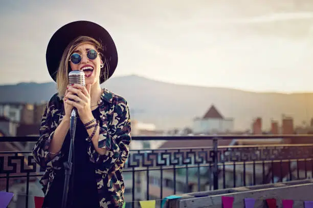 Photo of Young girl is singing on the roof terrace party