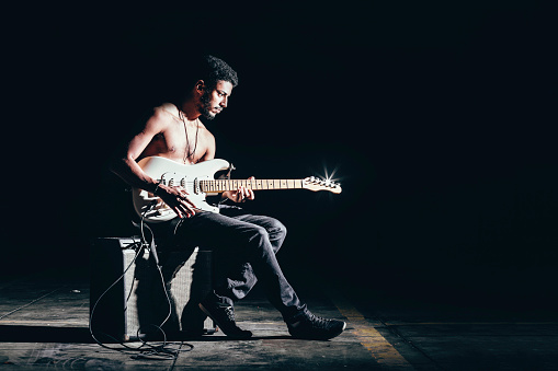 Young Afro American man playing electric guitar