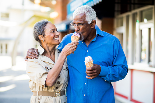 A senior african american couple enjoy an evening on the town with ice cream sharing a bite
