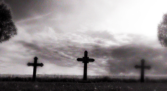 Cross, three cross in graveyard, black and white processed, harshly processed to create a moody feeling