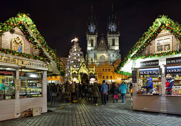 Christmas market at the Old Town Square of Prague in night, Czech Republic Prague, Czech Republic - December 5, 2017: Christmas market at the Old Town Square with the city's main Christmas tree in night. Two market stalls with food and drinks are located in the foreground. The Gothic church of Our Lady before Tyn is located on the background. Unknown people walk around the square and climb to the lookout platform. prague christmas market stock pictures, royalty-free photos & images