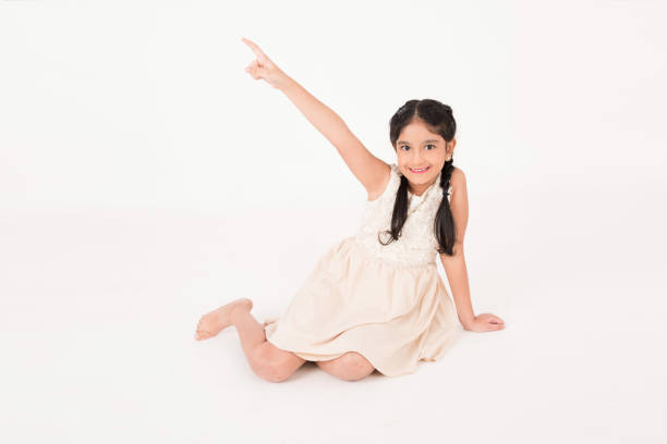 Female child sitting on the floor and indexing with white background