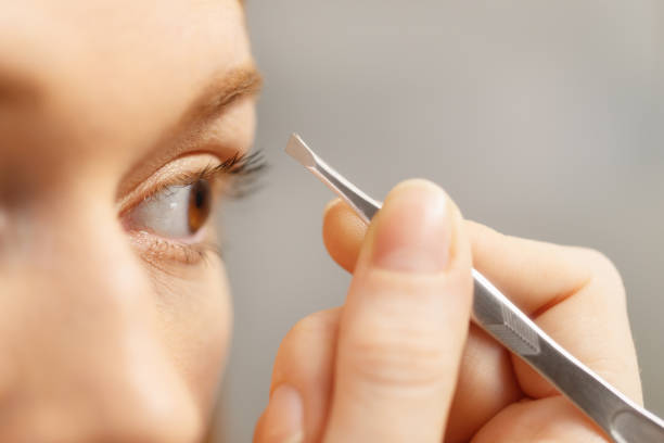 istock Young Woman Removing Eyebrows Looking At Mirror In Bathroom 898262006