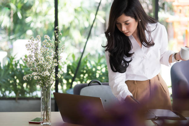 istock businesswoman write note on notebook at workplace. startup woman working with computer at office. young female entrepreneur hold coffee cup with paperwork on table. 898262788