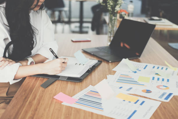 istock businesswoman write note on notebook at workplace. startup woman working with business plan report document at office.  young female entrepreneur analyze accounting market data.  financial adviser with paperwork on table. 898262812