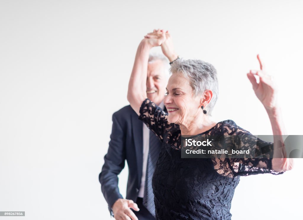 Elegantly dressed couple dancing exuberantly Close up of elegantly dressed older man and woman dancing exuberantly against neutral background (selective focus) Dancing Stock Photo