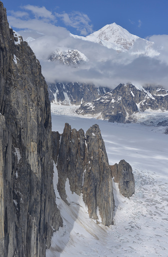Vertical cliffs of Ruth Gorge in the Alaska Range mountains. Denali (former) Mt. McKinley, the highest mountain in North America, visible in the background.