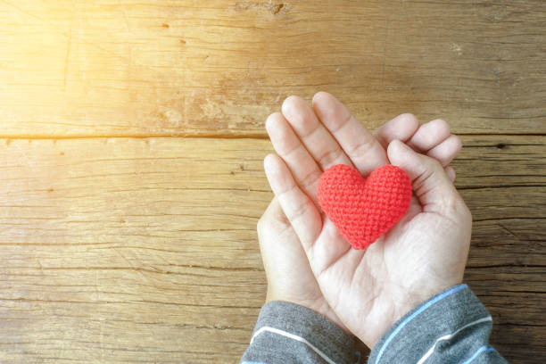 istock Man holding a single red heart on wooden 898269570