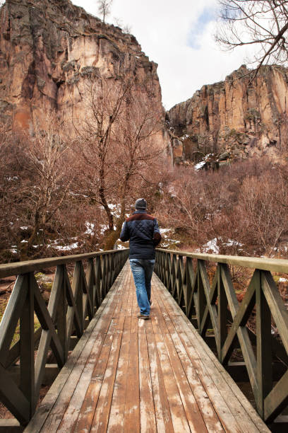 Man walking on wooden bridge - Ihlara valley Man walking on wooden bridge, walking, Ihlara valley, railing, cappadocia winter photos stock pictures, royalty-free photos & images