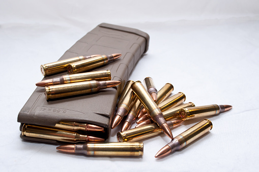 Several .223 caliber rounds and a loaded magazine on a white background