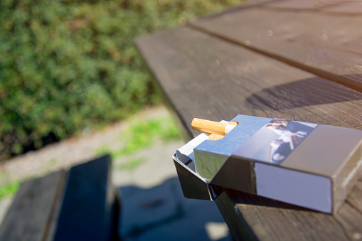 Open pack of cigarettes on the wooden table in the park