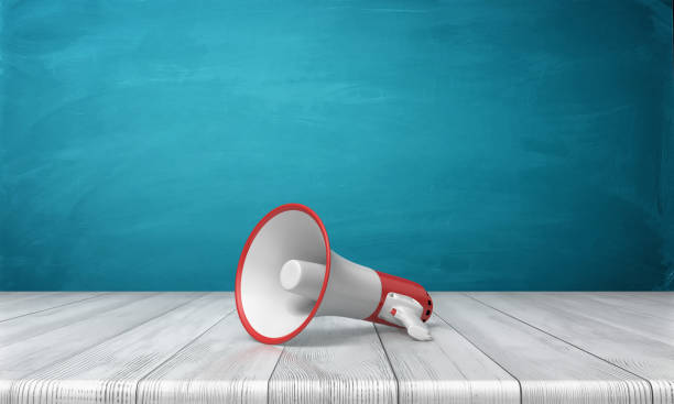 istock 3d rendering of a single red and white megaphone lying down on a wooden desk on blue background 898279178