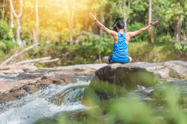 istock Young asian man in a yoga pose at the waterfall 898280854