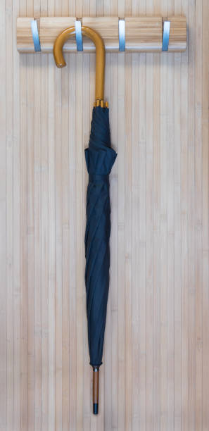 istock Black umbrella hang on hook rack, wooden wall 898293480