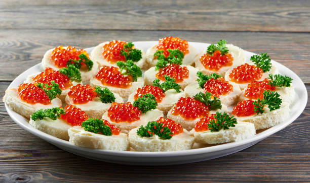 a big plate served with red caviar canapees - plank bread caviar close up imagens e fotografias de stock