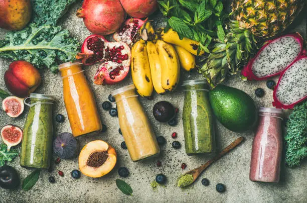 Photo of Colorful smoothies in bottles with fresh tropical fruit and superfoods
