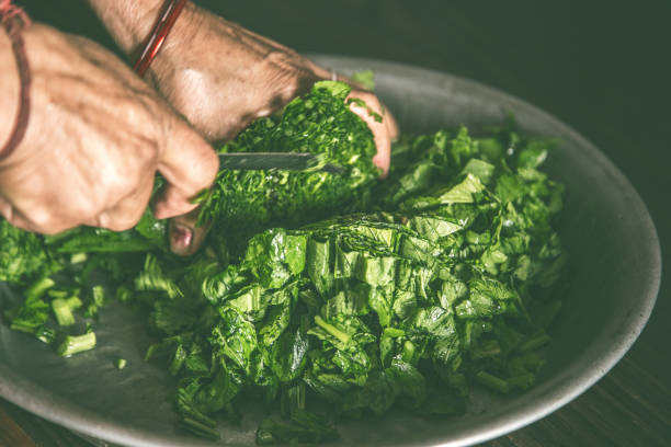 istock Woman hand cutting raw green vegetable on  utensil 898312832