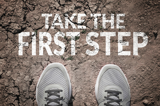 Take the first step text and sneakers on dry land top view