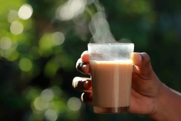 Hand holds a glass of hot tea in outdoor