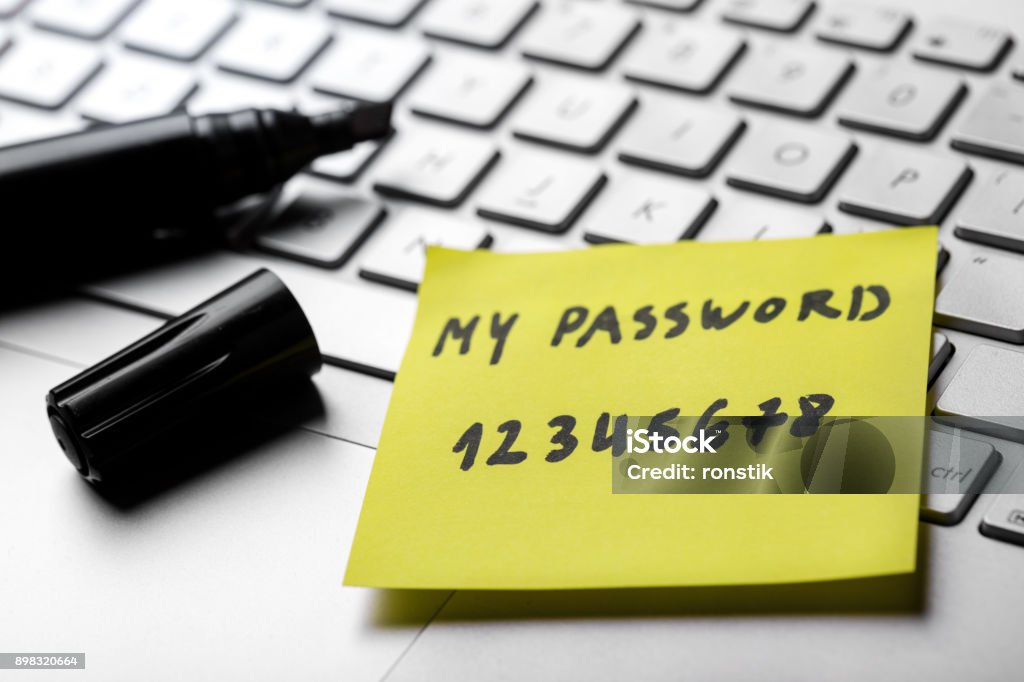 sticky note with weak easy password on laptop keyboard Password Stock Photo