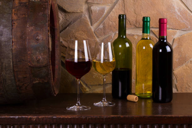 istock Red and white wine beside old cask in wine cellar 898321568
