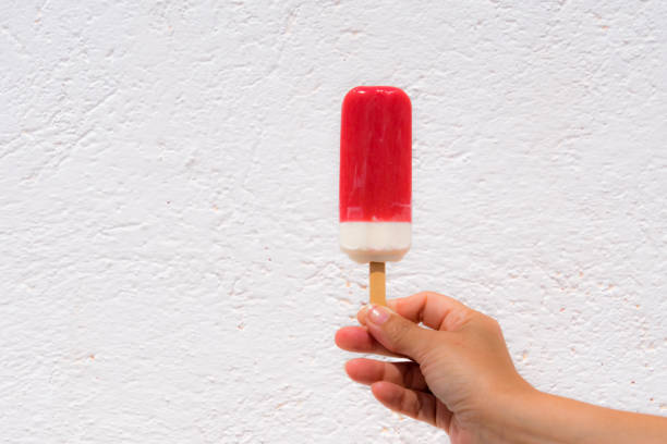 istock Close-Up Of Hand Holding Flavored Ice Against Wall 898321846
