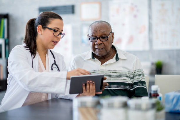 médecin avec une tablette pc - patient doctor hospital senior adult photos et images de collection