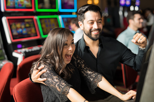 Good looking young couple celebrating and looking excited about hitting the jackpot in a slot machine at a casino